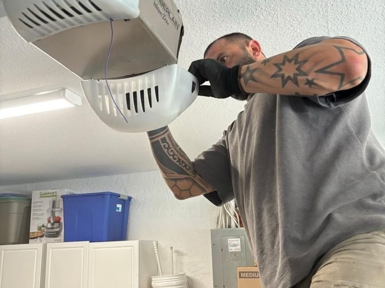 Technician servicing a ceiling-mounted garage door opener